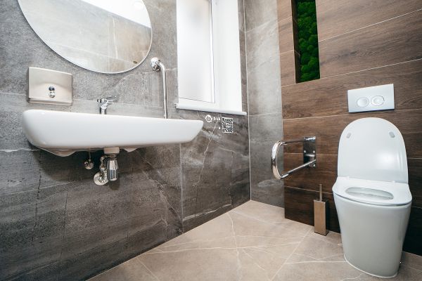 White ceramic toilet bowl near light grey wall.